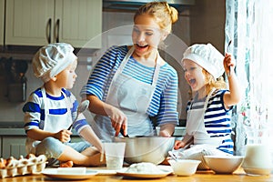 Happy family in kitchen. mother and children preparing dough, ba