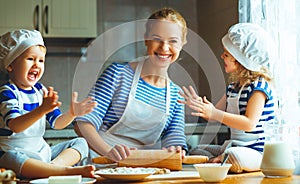 Happy family in kitchen. mother and children preparing dough, ba