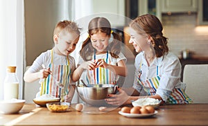 Happy family in kitchen. mother and children preparing dough, bake cookies