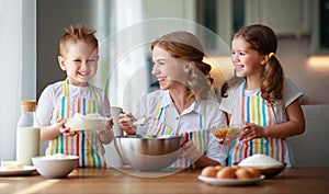 Happy family in kitchen. mother and children preparing dough, bake cookies photo