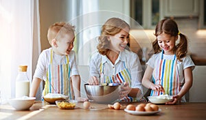 Happy family in kitchen. mother and children preparing dough, bake cookies