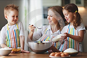 Happy family in kitchen. mother and children preparing dough, bake cookies