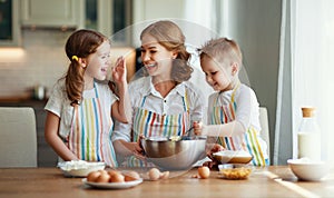 Happy family in kitchen. mother and children preparing dough, bake cookies