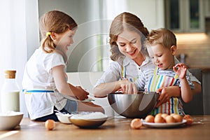 Happy family in kitchen. mother and children preparing dough, bake cookies