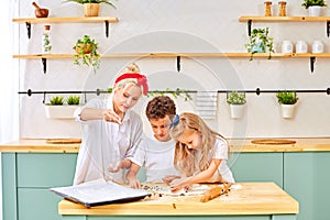 Happy family in the kitchen. mother and children preparing the dough, bake cookies