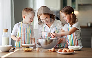 Happy family in kitchen. mother and children preparing dough, bake cookies