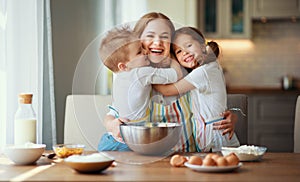 Happy family in kitchen. mother and children preparing dough, bake cookies