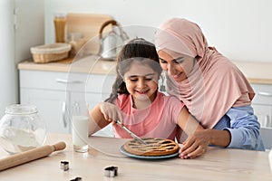 Happy Family In Kitchen. Muslim Mom And Daughter Cutting Homemade Pie