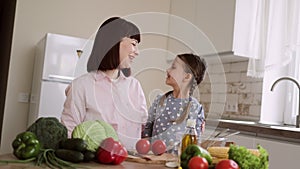 Happy family in the kitchen. Young mother and child daughter hugging and looking at each other