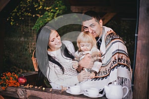 Happy family in a knitwear drinking tea in aforest photo