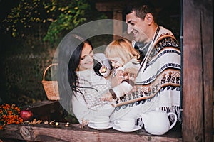 Happy family in a knitwear drinking tea in aforest photo
