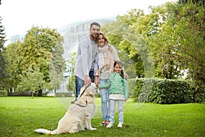 Happy family with labrador retriever dog in park