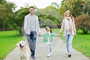 Happy family with labrador retriever dog in park