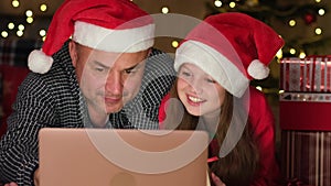 Happy family with laptop on winter evening, enjoying warm Christmas atmosphere