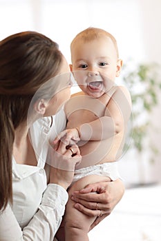 Happy family laughing faces, mother holding cute child baby boy. Young woman and her small son have a fun pastime.