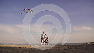 Happy family launches a kite at sunset. early spring on the sea. children spend time with parents outdoors. Father