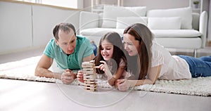 Happy family laying on carpet playing with the wooden blocks