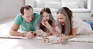 Happy Family Laying On Carpet Playing With The Wooden Blocks
