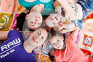 Happy family lie on colorful blanket, top view.