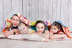 Happy family lie on the floor under colorful blanket