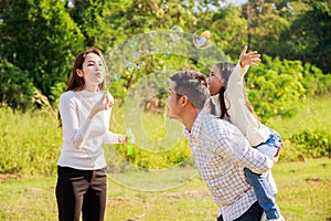 Happy family life concept. Asian parents Father, Mother and the little girl enjoying and fun during playing soap bubbles. family