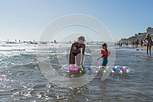 Happy family lifestyle.  Smiling young mother and son jumping and splashing with fun in breaking waves