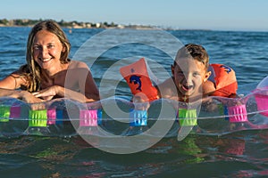 Happy family lifestyle.  Smiling young mother and son jumping and splashing with fun in breaking waves