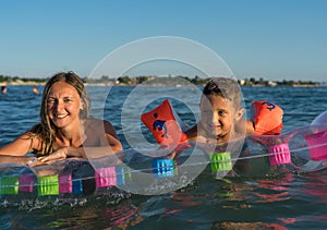 Happy family lifestyle.  Smiling young mother and son jumping and splashing with fun in breaking waves