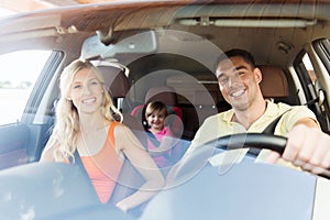 Happy family with little child driving in car