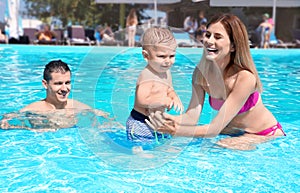 Happy family with little child resting in swimming pool