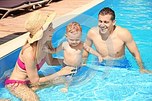 Happy family with little child resting in swimming pool