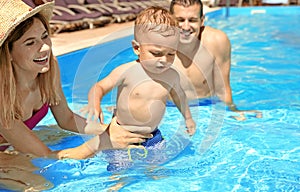 Happy family with little child resting in swimming pool