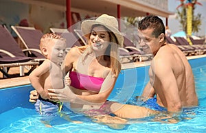 Happy family with little child resting in swimming pool