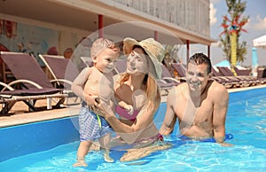 Happy family with little child resting in swimming pool