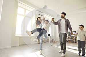 Happy family with little children having fun in sunny living-room of new apartment