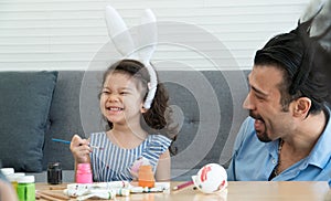 Happy family Little daughter and father wearing bunny ears paint Easter eggs