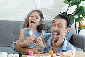 Happy family Little daughter and father wearing bunny ears paint Easter eggs