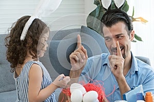 Happy family Little daughter and father wearing bunny ears paint Easter eggs