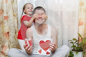 Happy family, little daughter hugs dad and covers his eyes with his palms. Father`s day