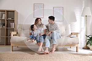 Happy family with little daughter sitting on sofa in room