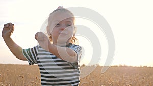 A happy family. A little girl runs across a wheat field. Happy child playing catch-up at sunset. The kid runs across the