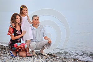 Happy family with little girl on stony beach