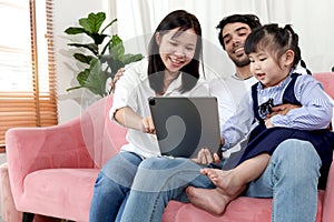 Happy family in living room, Chubby little girl daughter with her mother and father using tablet in living room. Kid spending
