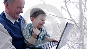 Happy family looking together in laptop monitor at home on windowsill