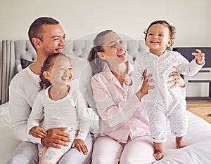 Happy family, love and morning bonding with parents, child and baby playing in the bedroom and having fun together at