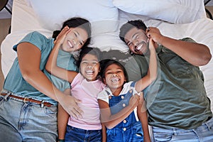 Happy family, love and morning smile with parents and children lying and playing in bed for fun together at home from