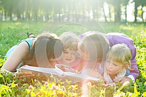 Happy family lying on the grass and reading a book