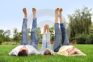 Happy family lying on green grass in park
