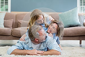Happy family lying heaped on carpet in living room