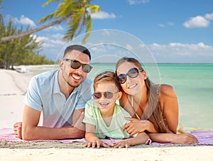 happy family lying over tropical beach background